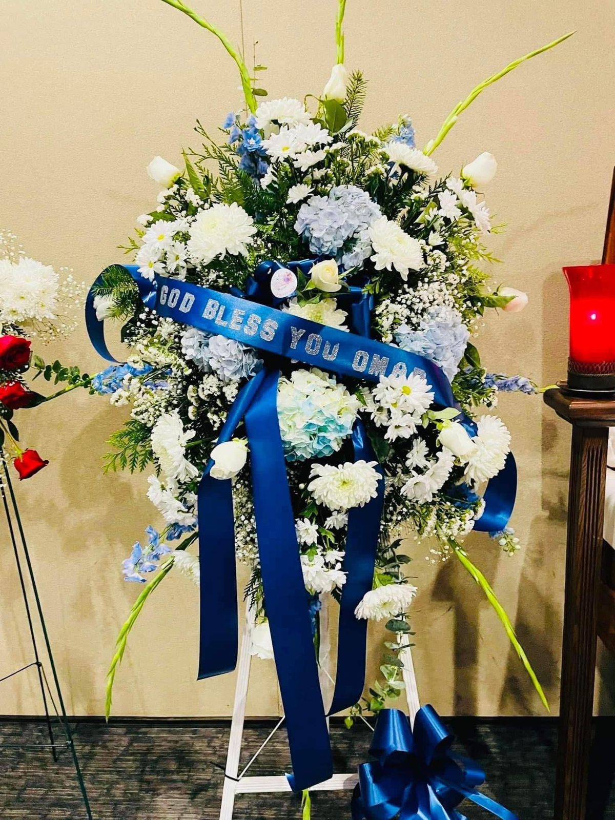 Blue and white sympathy standing spray with hydrangea, mums and gladiolus and a personalized memorial ribbon