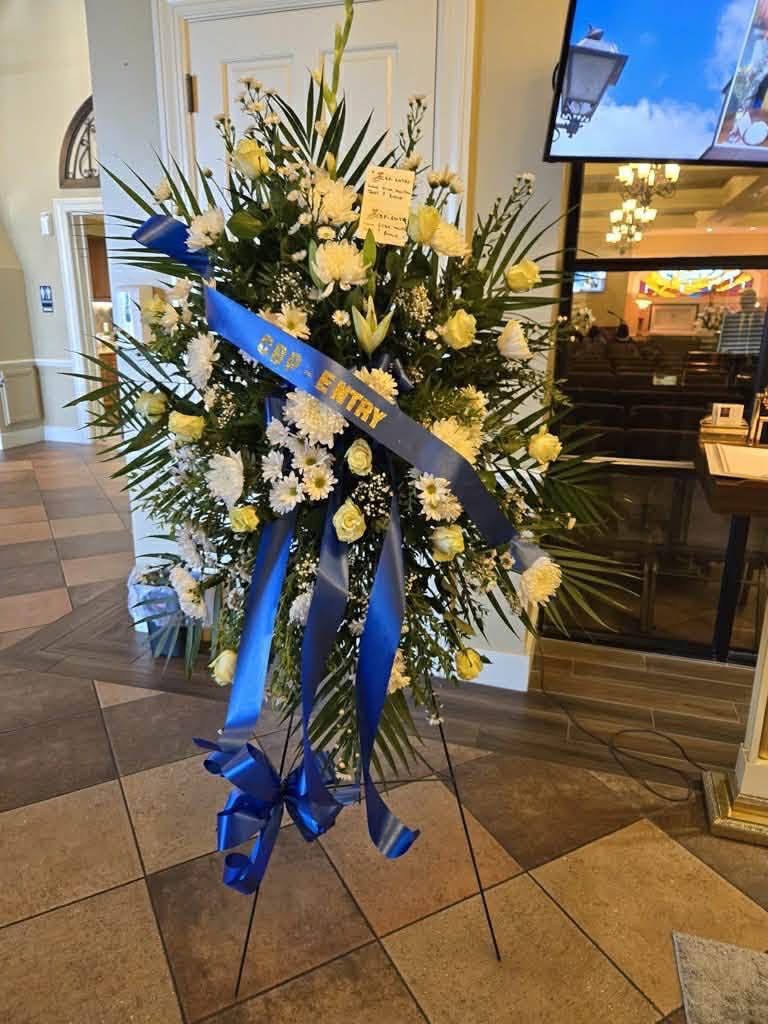 White funeral standing spray with roses and mums displayed at a Rio Grande Valley funeral home service